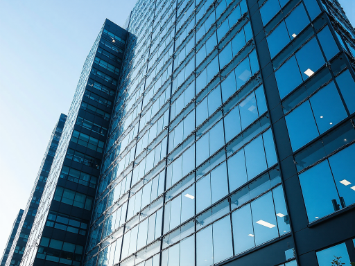 Modern office building exterior with glass facade, reflecting sunlight, surrounded by green plants, showcasing a modern corporate image